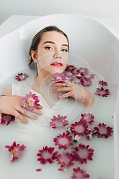 Woman lies in a bath with milk among the flowers