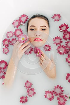 Woman lies in a bath with milk among the flowers