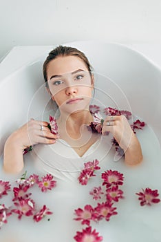 Woman lies in a bath with milk among the flowers