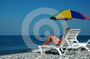 Woman lies in chaise longue on beach