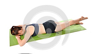 Woman lies face down on a sports mat and does an exercise to stretch her legs.