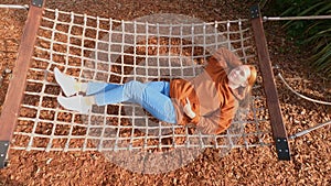 A woman lies in a hammock in an autumn park. Rest in the fresh air.