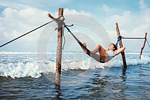 Woman lies in hammock over the waves and enjoy with sun light