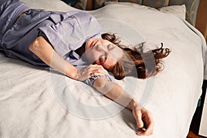 A woman lies in peaceful repose on a bed, surrounded by the comforts of home