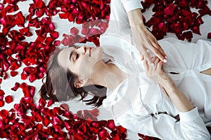 beautiful woman lies in the petals of a red rose