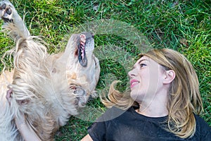 woman lies with a retriever dog on the lawn in the park. Close-up