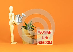 Woman life freedom symbol. Concept words Woman Life Freedom on wooden blocks on a beautiful orange table orange background.