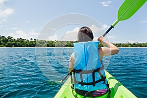 Woman with lifejacket kayaking in tropical island ocean on vacation.