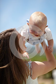Woman, lift baby outdoor and happy with care, love and bonding on holiday, summer sunshine and playing together. Mother