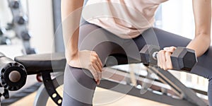 A woman is lifting the Dumbbell up to her head to strengthen her arms and shoulders. The trainers are consulting for exercisers