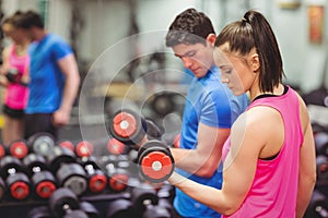 Woman lifting dumbbells with her trainer