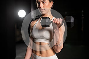 Woman lifting dumbbells, training with light weights. Routine workout for physical and mental health.