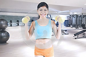 Woman lifting two dumbbells in the fitness center