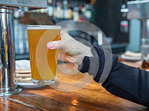 Woman lifting up pint glass of IPA beer in a bar