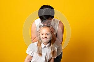 Woman in light clothes have fun with cute child baby girl. Mommy little kid daughter isolated on yellow background