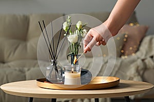 Woman lighting candle at table in living room