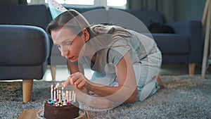 Woman lighting candles on birthday cake, celebrating birthday at home