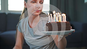 Woman lighting candles on birthday cake, celebrating birthday at home alone