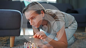 Woman lighting candles on birthday cake, celebrating birthday at home alone