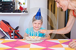 Woman lighting candles on birthday cake and child looking laughing