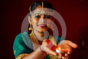 Woman lighting diyas with nuth nath nose piercing and the golden teak with traditionak fashion sari