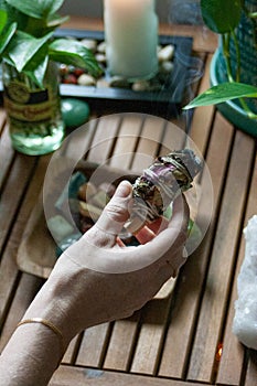 Woman Lighting a Smudge Stick With Crystals