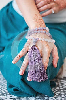 Woman with lilac mala beads on her hands henna mehendi