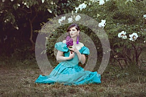 Woman with a lilac sits on the grass.