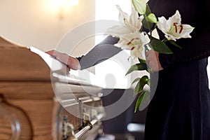 Woman with lily flowers and coffin at funeral