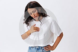 Woman ling pain heart pain, pre-stroke condition, spasm in the chest area at a young age, a woman in a white t-shirt and