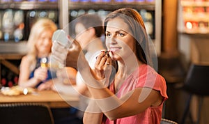 Woman with lipstick applying make up at restaurant