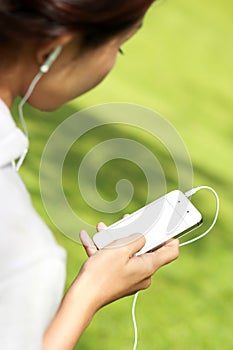 A woman listening a music in mobilephone using earphone