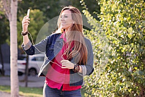 Woman listening music from smart phone with headphones outdoor a