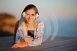 Woman listening to music on the beach looks at you