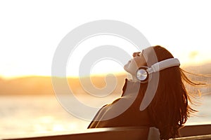 Woman listening to music breathing on a bench in winter