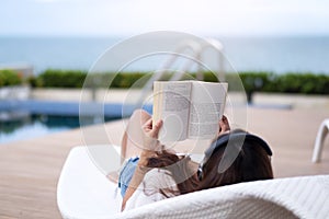 A woman listening to music with headphone and reading a book