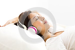 Woman listening to music with headphones in bed
