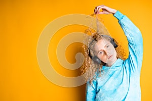 Woman listening to music with headphones winding a lock of hair on her finger