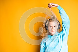 Woman listening to music with headphones winding a lock of hair on her finger