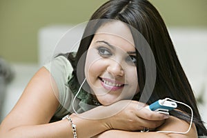 Woman Listening To Music On MP3 Player At Home