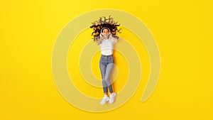 Woman Listening To Music Online Wearing Headphones On Yellow Background