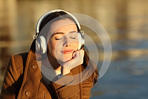 Woman listening to music relaxing at sunset in winter
