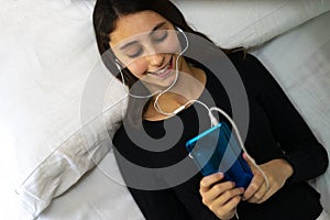 Una mujer escuchando sobre el música sobre el blanco una cama 