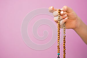 Woman, lit hand close up, counts Malas, strands of gemstones beads used for keeping count during mantra meditations on