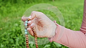 Woman lit hand close up counts rosary - malas strands of gemstones beads used for keeping count during mantra