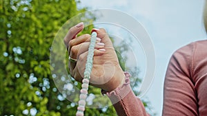 Woman lit hand close up counts rosary - malas strands of gemstones beads used for keeping count during mantra