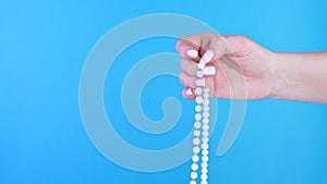 Woman lit hand counts mala beads strands of gemstones used for keeping count during mantra meditations. Blue background