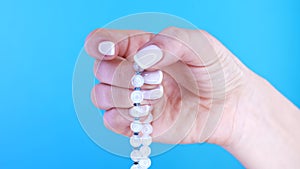 Woman lit hand counts mala beads strands of gemstones used for keeping count during mantra meditations. Blue background