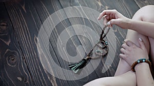 Woman lit hand counts mala beads strands of gemstones used for keeping count during mantra meditations. Lady sits on