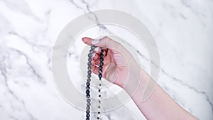 Woman lit hand counts mala beads strands of gemstones used for keeping count during mantra meditations. Marble light